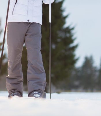 Human legs in warm winter pants during skiing in snowdrift on wintery day